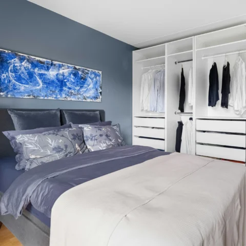 Dormitorio con paredes azul grisáceo y armario blanco